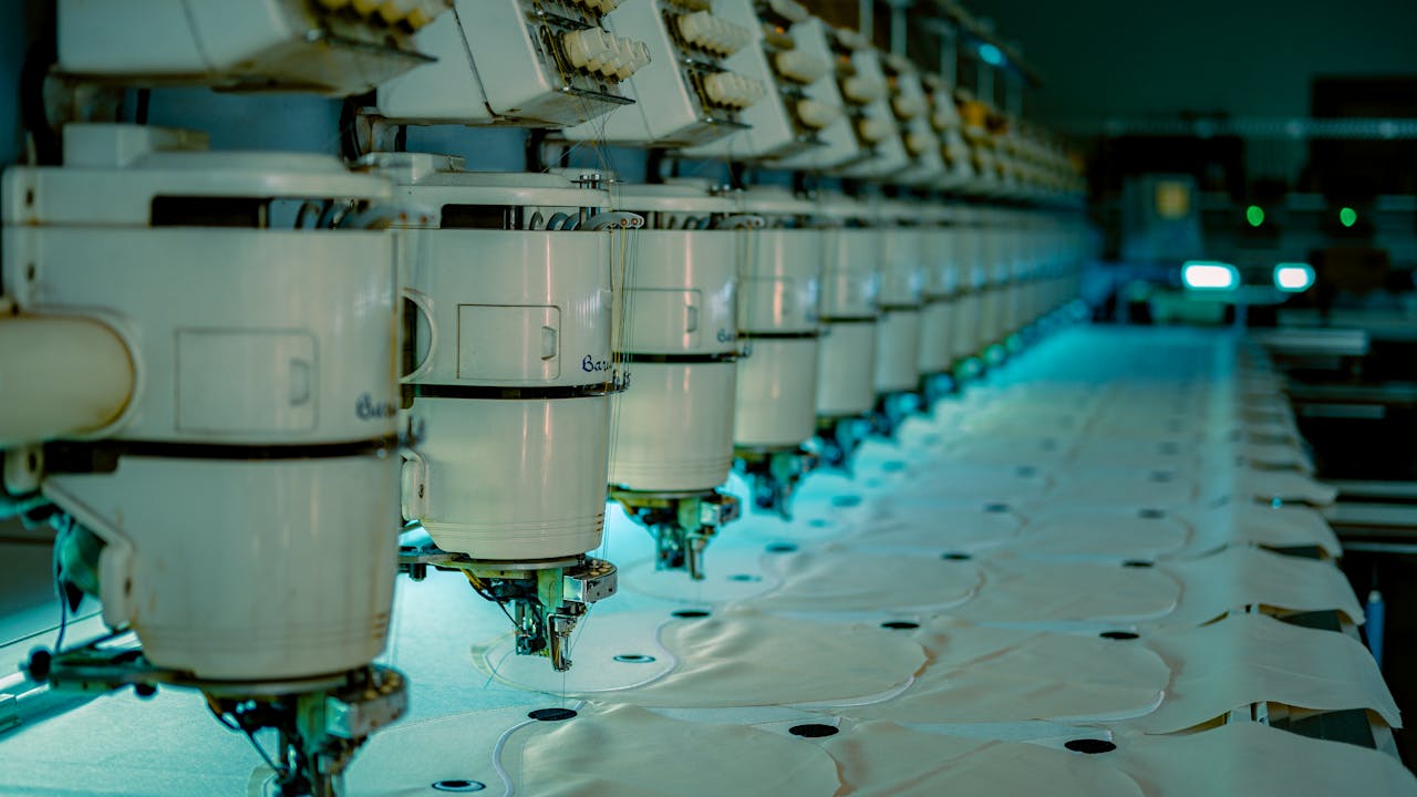 gallery-1 Row of industrial sewing machines in a textile factory producing garments.