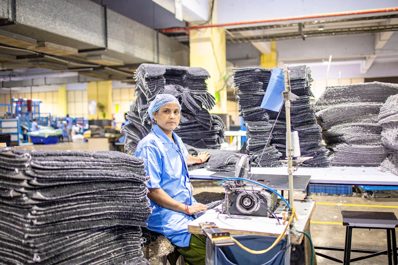 gallery-2 A dedicated worker operates machinery in a busy textile factory, showcasing a blue-collar work environment.