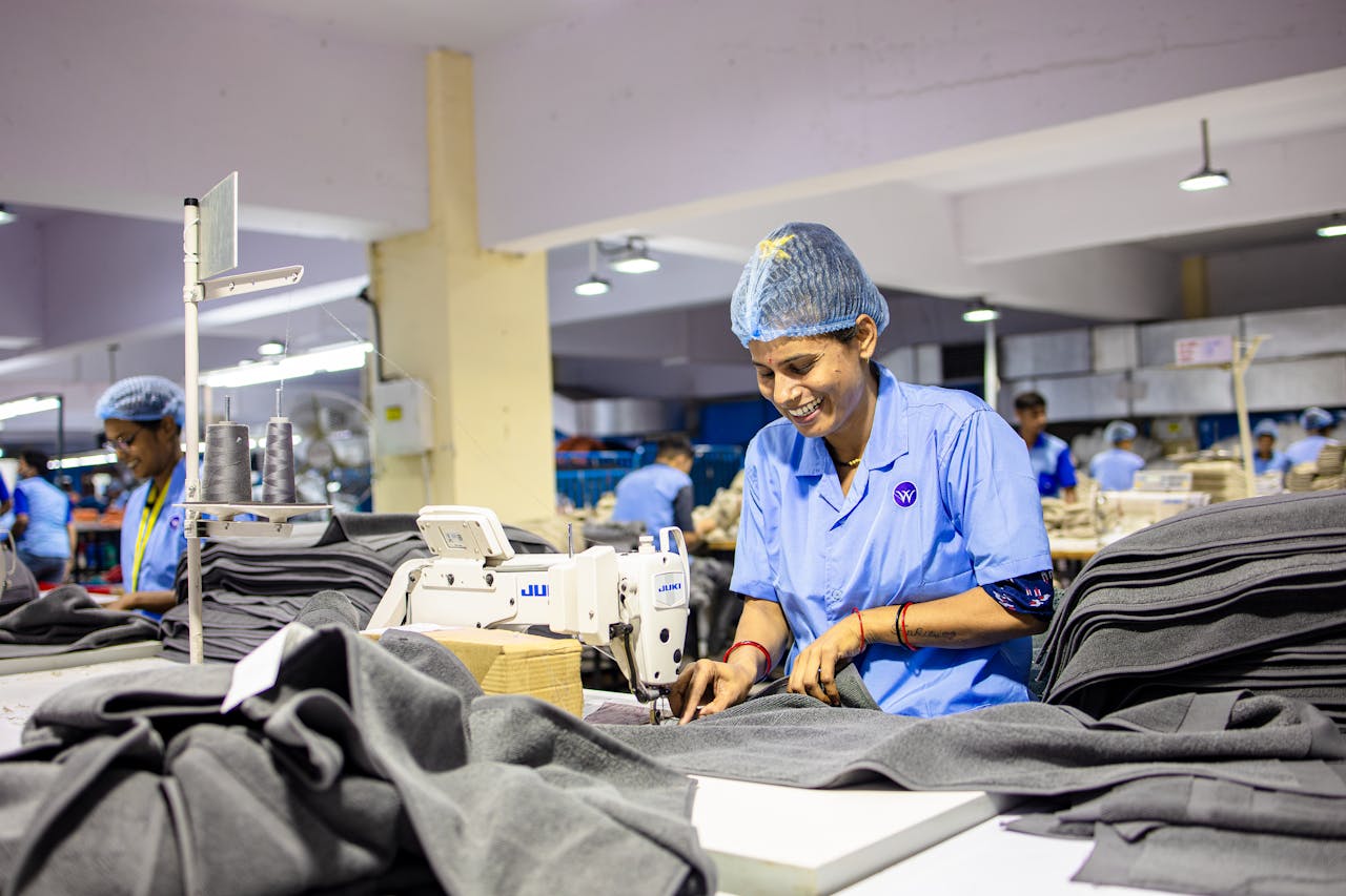 The Art of Drawing Readers In: Your attractive post title goes here Female worker operates sewing machine in bustling textile factory, smiling and focused.