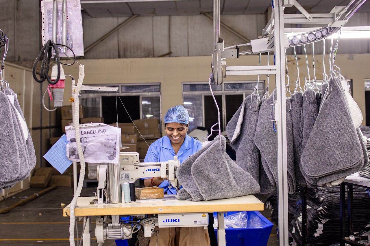 services-01 A factory worker sewing textiles on an industrial machine in a modern garment manufacturing facility.