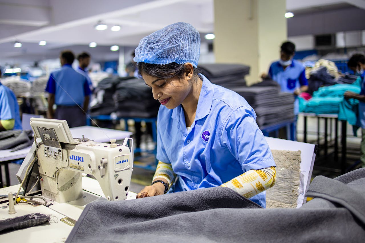why-choose-us A dedicated textile worker operating a sewing machine in an industrial factory environment.
